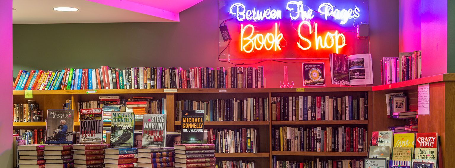 Between the Pages book shop with neon sign and shelves of books