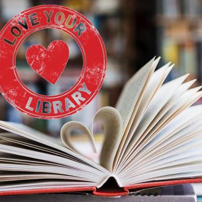 Open book with a heart shaped folded into it and a Love Your Library  stamp