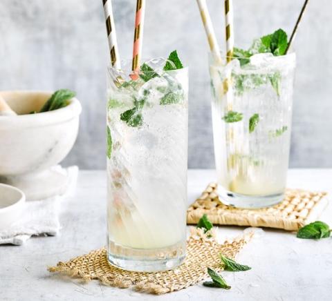 Two mocktails with mint in them against a marble background. 