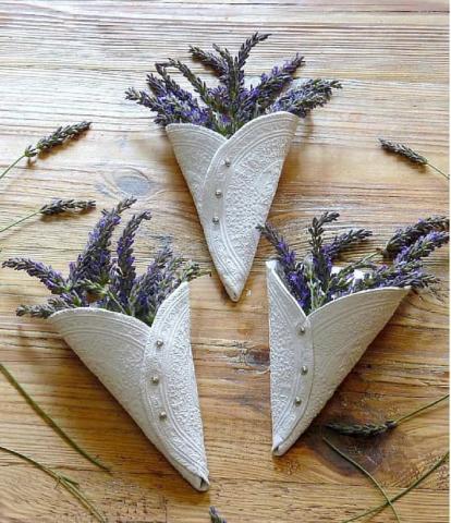 Three air dry clay cones with lavender in them against a wood background. 