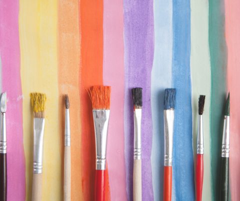 watercolor paint brushes in front of vertical stripes of different colors