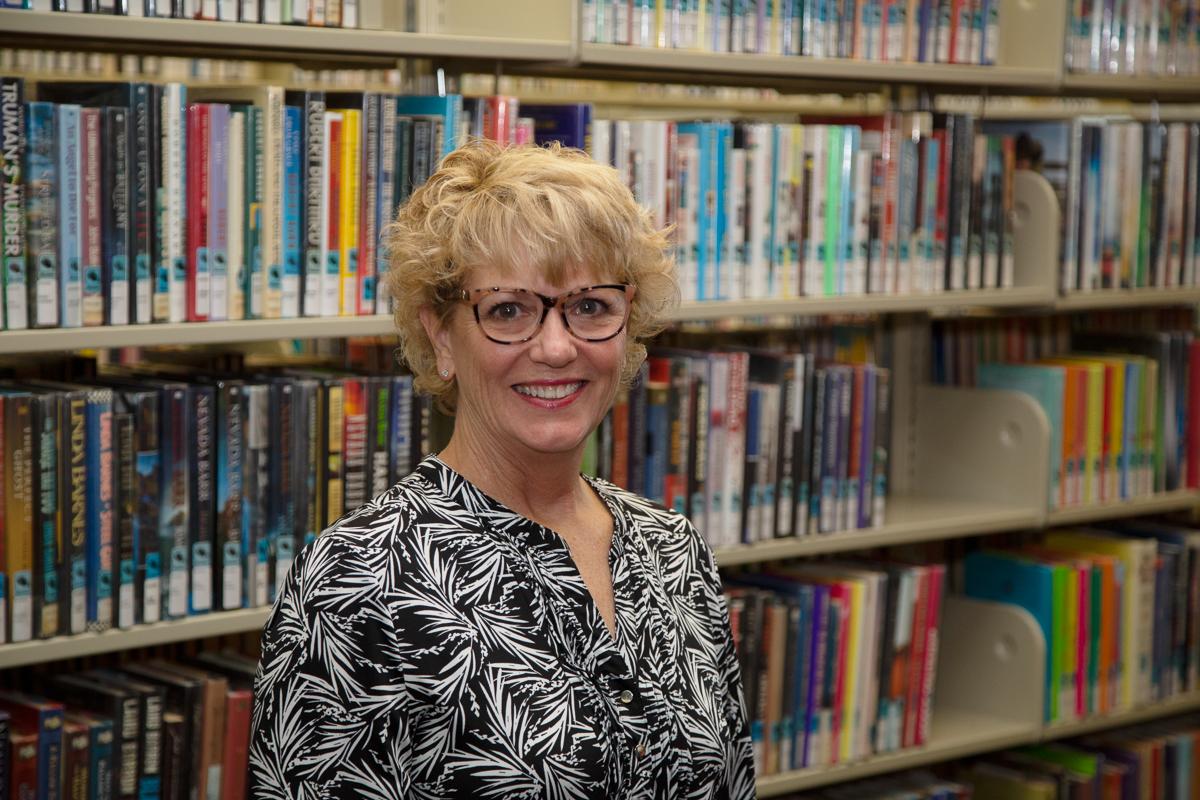 photo of Youth Services Librarian Robin Benham in front of a library book shelf
